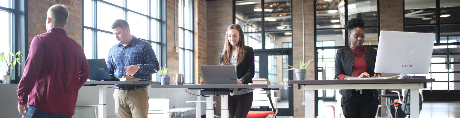 image of three people working at their stand up desk with their chairs behind them