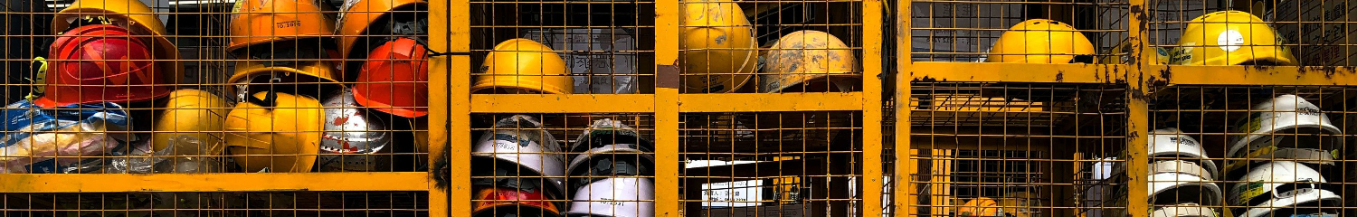 multiple safety helmets stored in a yellow cage