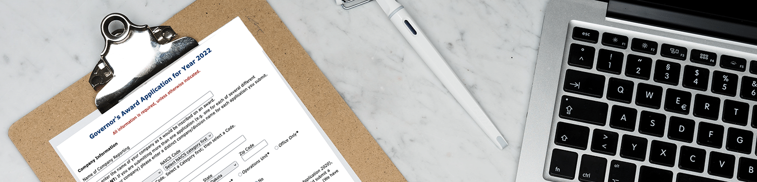 image of Governor's award app on a clipboard next to a apple laptop and a pen