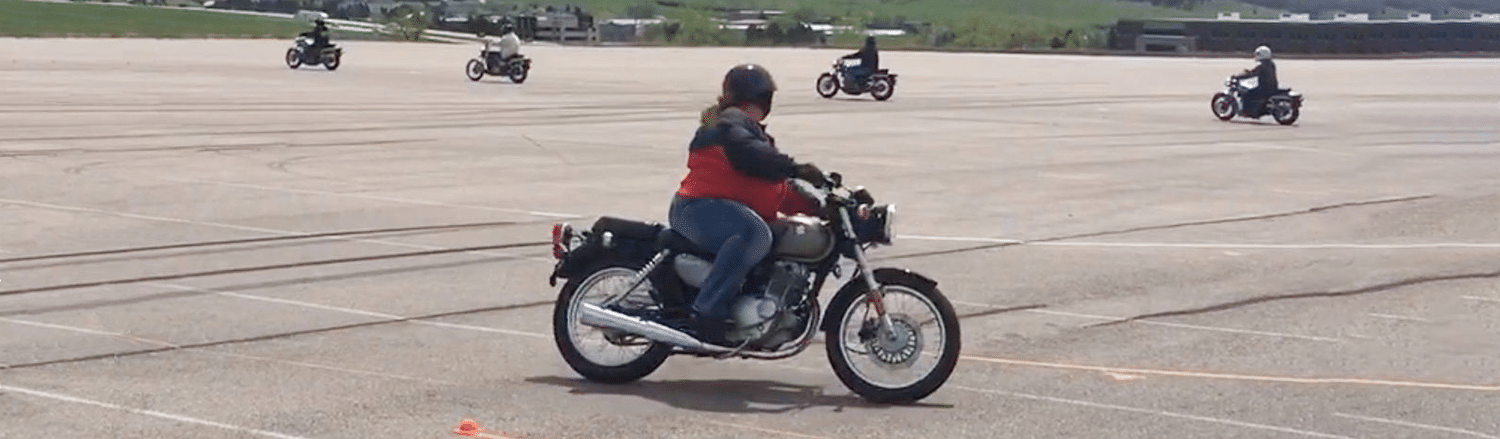 motorcycle training class practicing riding in a circle featuring woman on motorcycle in the foreground