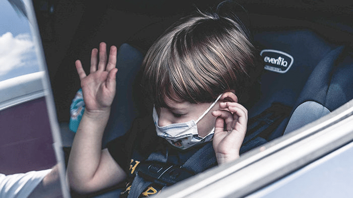 image of a young boy in carseat with a mask on